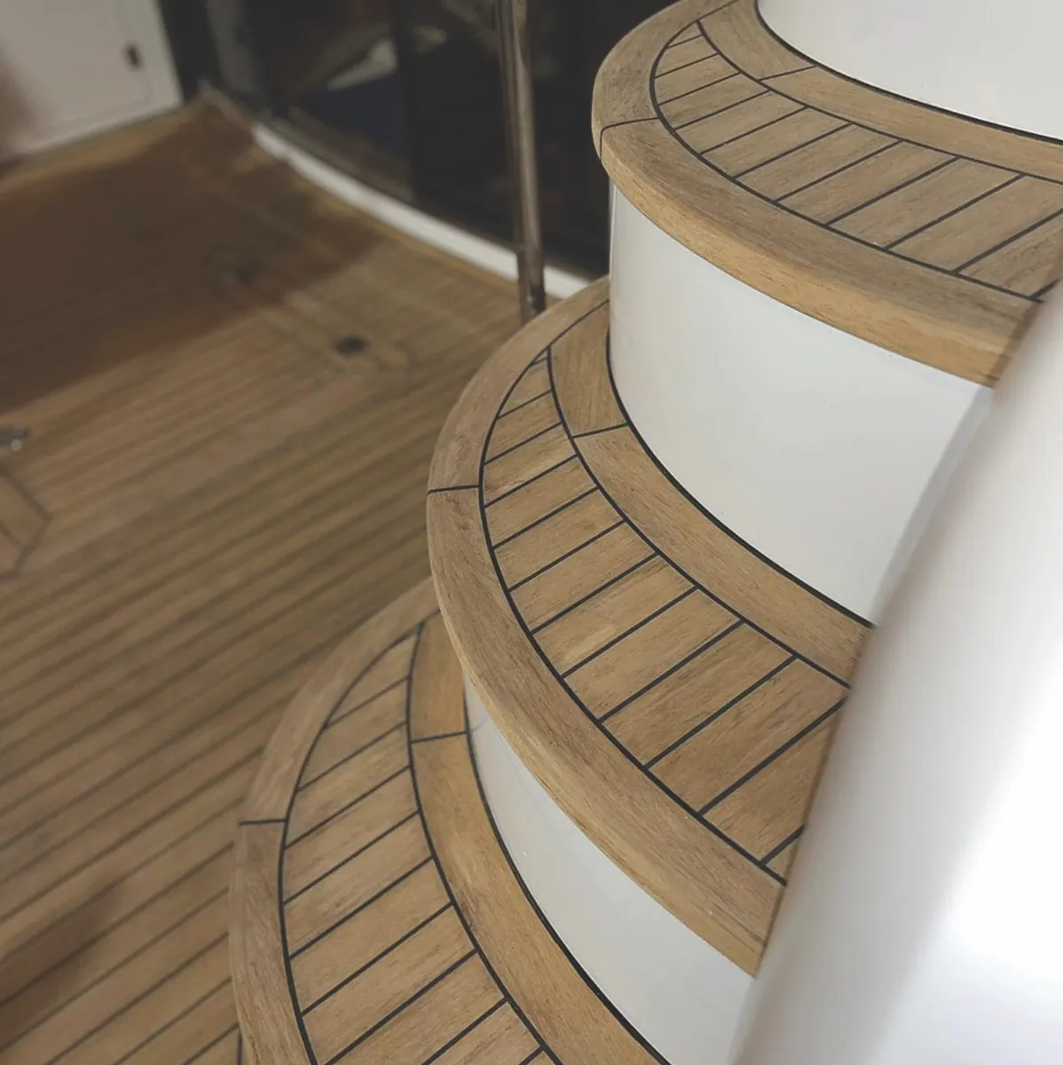 Zaobljene stepenice obložene EVO Decking sintetičkom tikovinom s crnim fugama